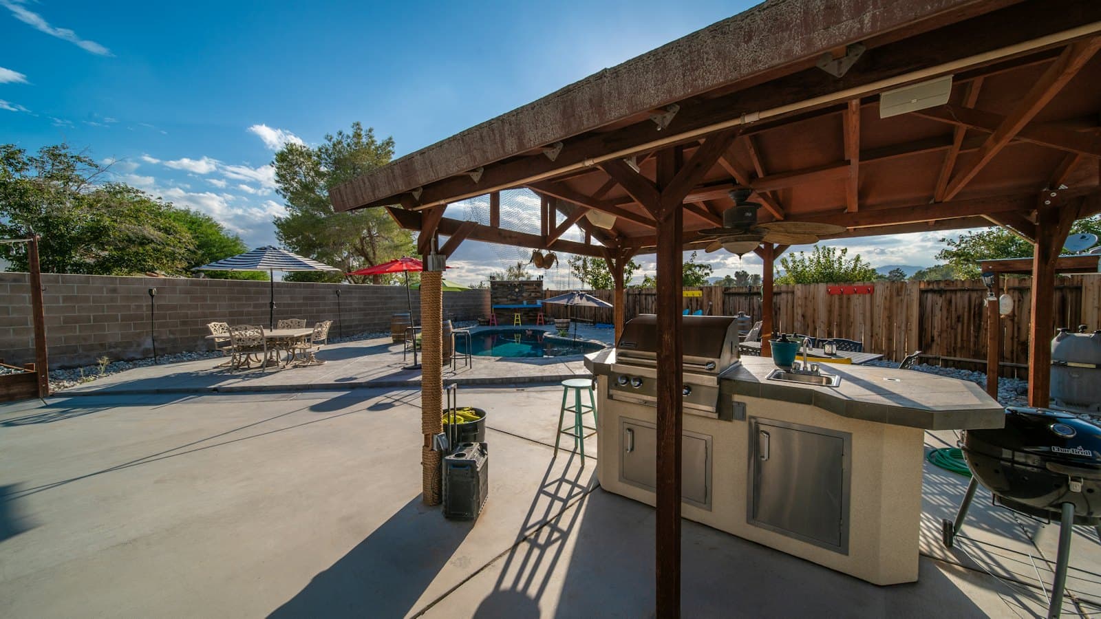 Covered backyard patio with an outdoor kitchen on a sunny summer day