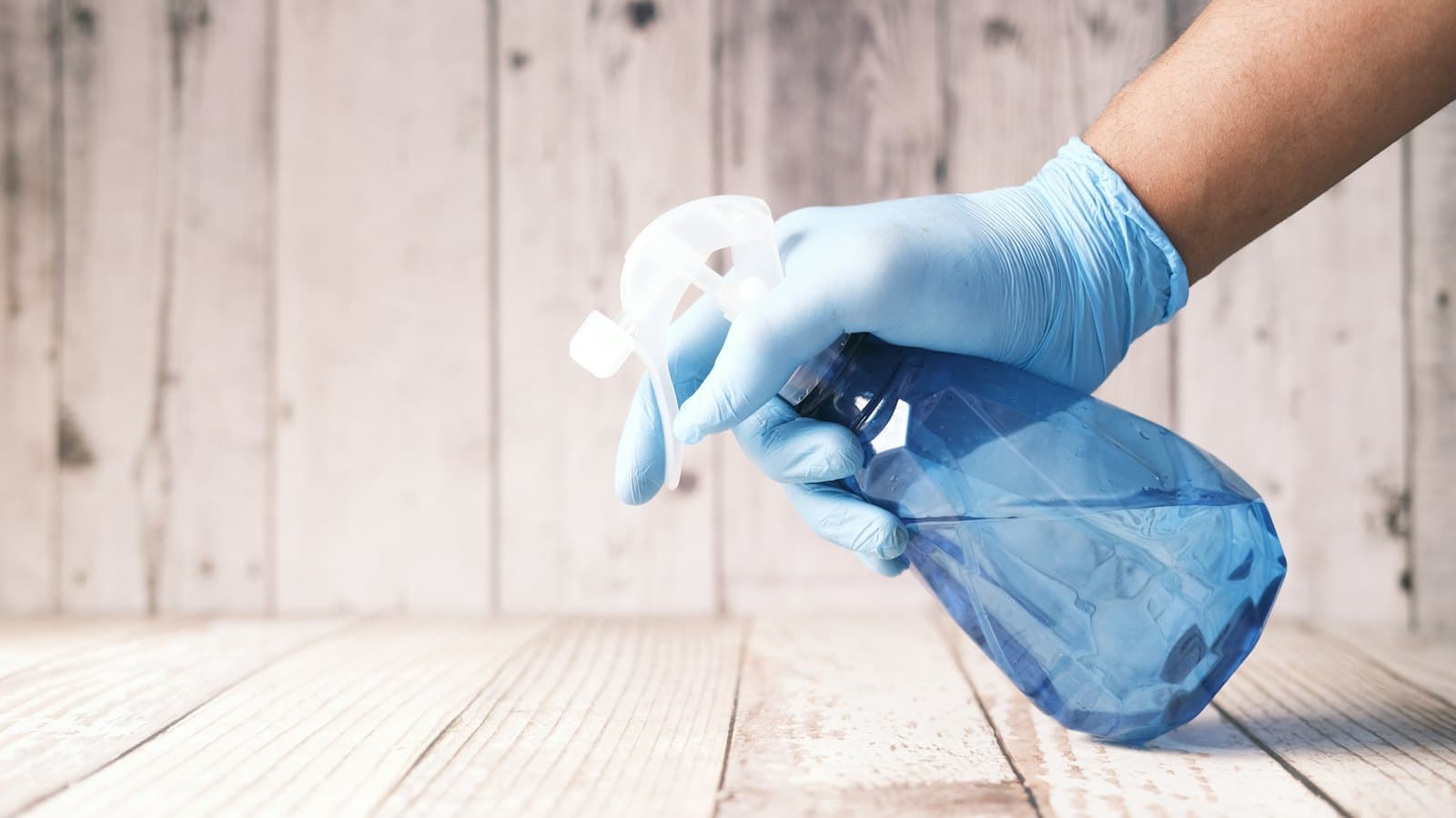 Gloved hand holding a spray bottle