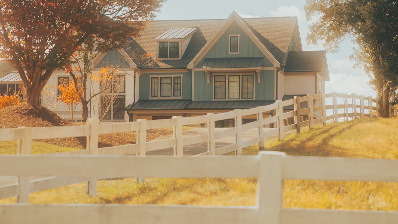 Farmhouse behind a white fence as the leaves change in autumn