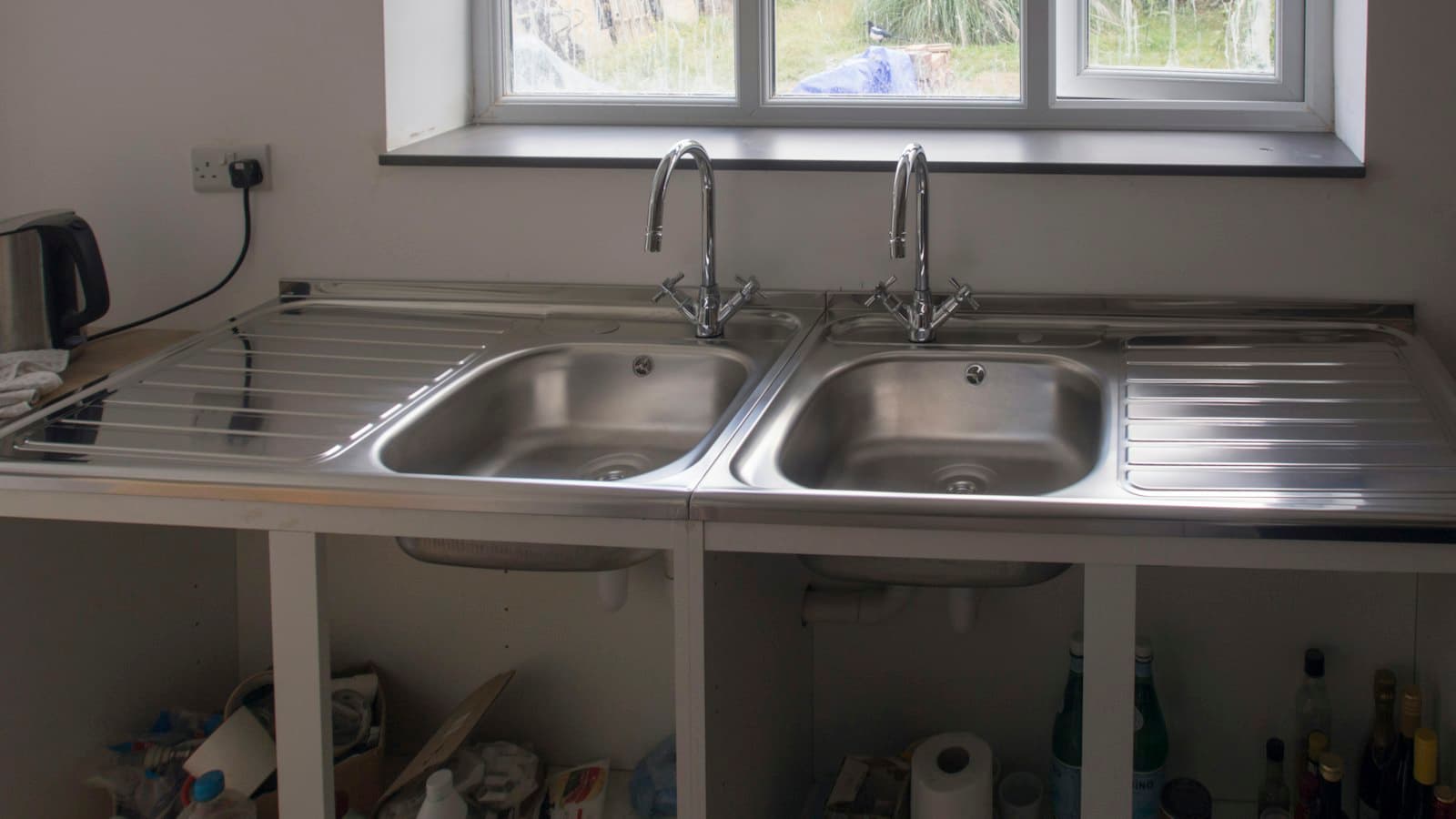 Open cabinet under a kitchen sink, a common insect hiding spot