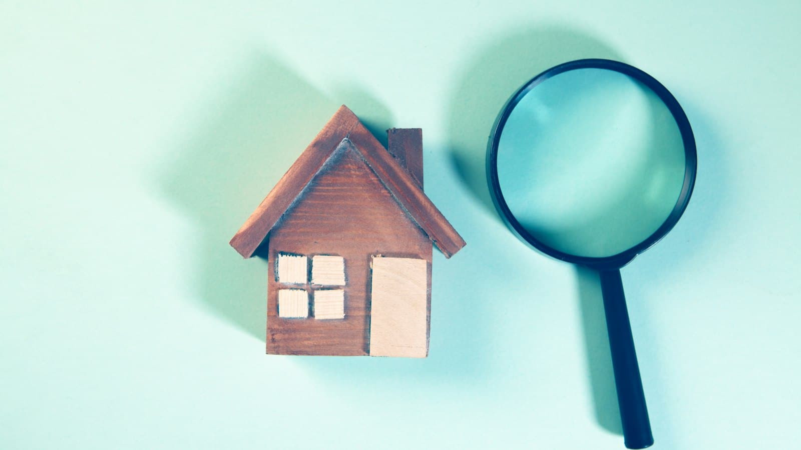 Magnifying glass beside a small model house