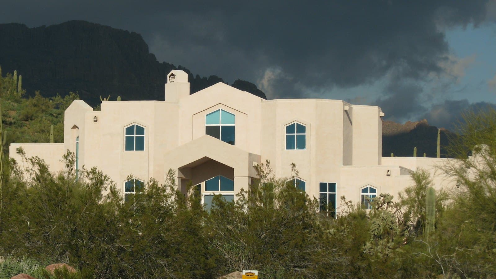 Stucco desert home under a stormy sky